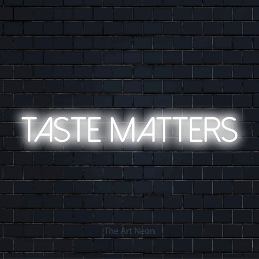 "Taste Matters" script-style LED neon sign on a black brick wall