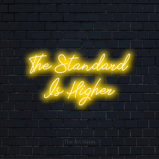 "The Standard Is Higher" glowing LED neon sign on a black brick wall