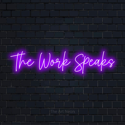 "The Work Speaks" script-style LED neon sign on a black brick wall