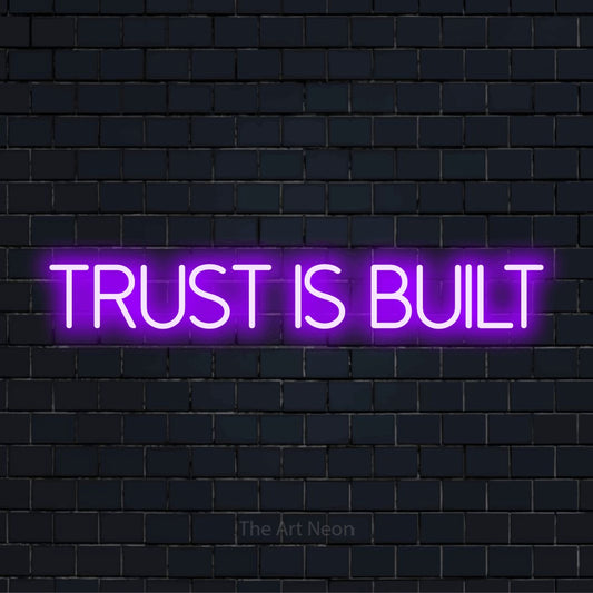 "Trust Is Built" text design with neon effect on a black brick wall