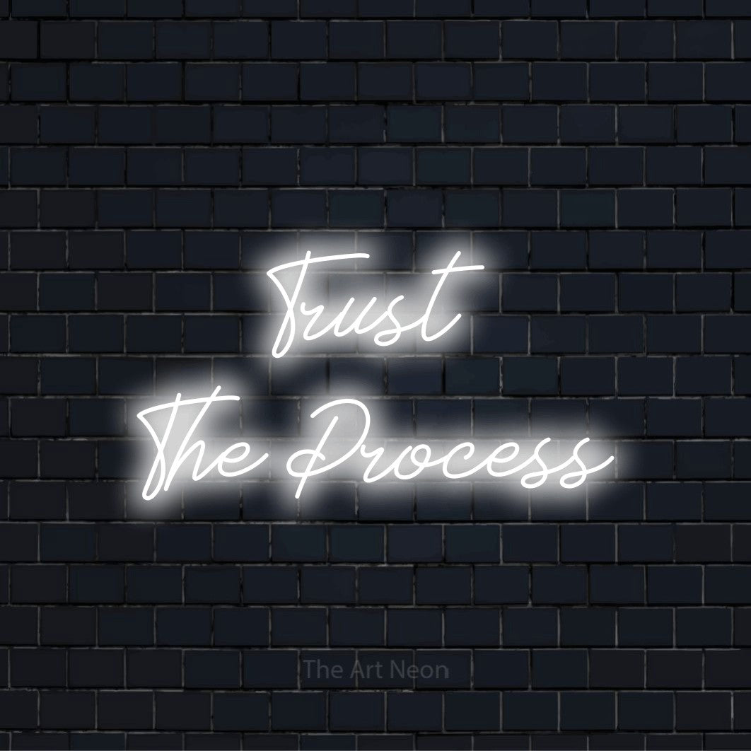 "Trust The Process" LED neon sign on a black brick wall