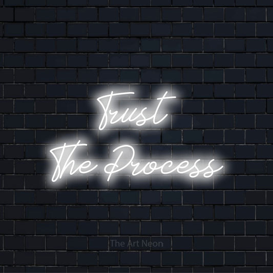 "Trust The Process" LED neon sign on a black brick wall