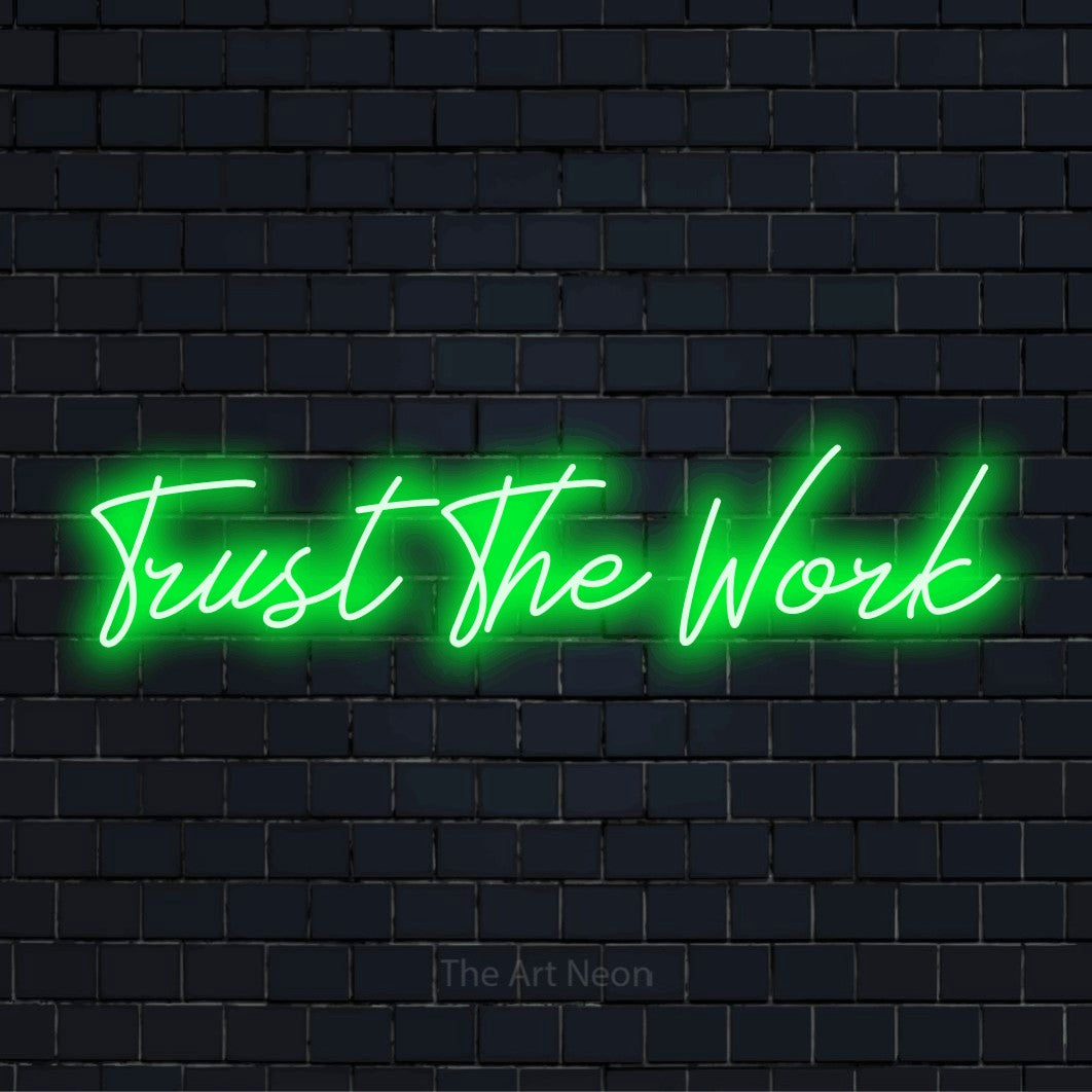 "Trust The Work" LED neon sign on a black brick wall