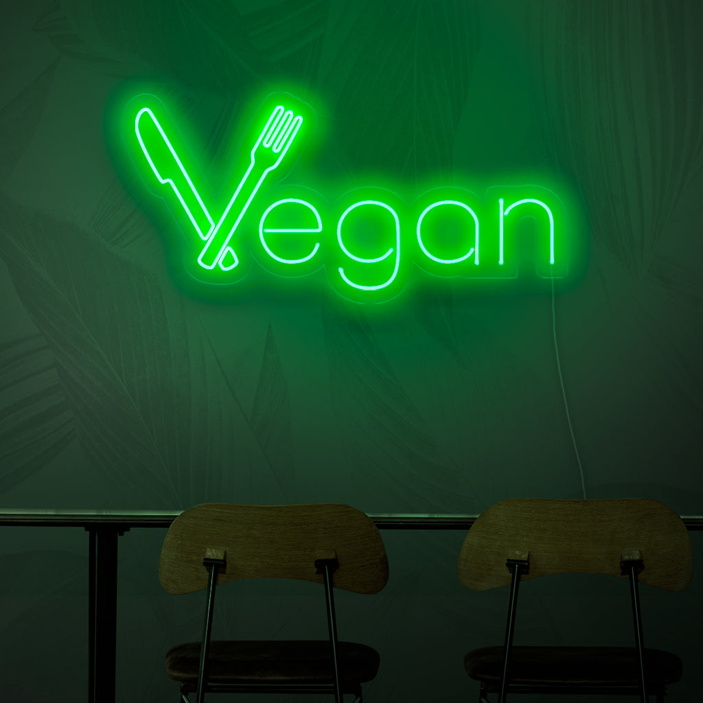Uma placa de neon com os dizeres "Vegano", representando o conceito de culinária à base de plantas com sua luz verde vibrante.