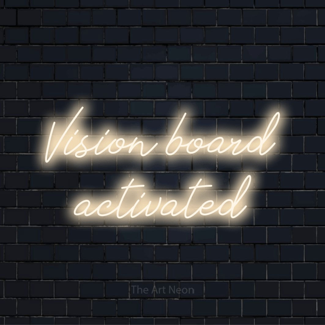"Vision Board Activated" neon text design on a black brick wall