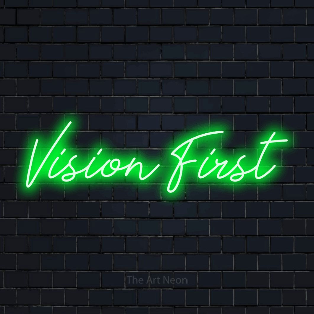 "Vision First" script-style LED neon sign on a black brick wall