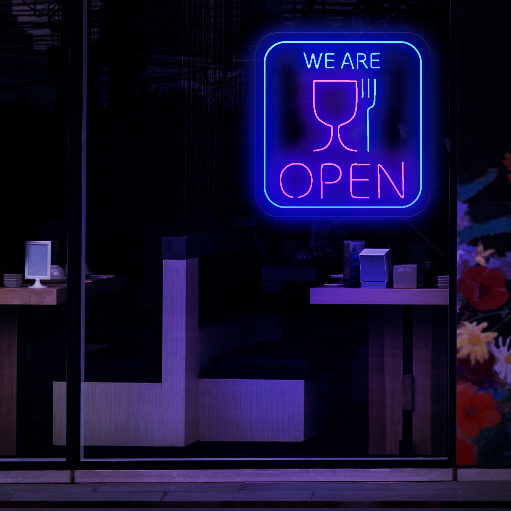 Uma placa de neon cativante com os símbolos de uma xícara e um garfo, indicando que um restaurante ou lanchonete está aberto.