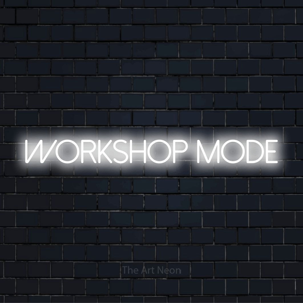 "Workshop Mode" glowing LED neon sign on a black brick wall