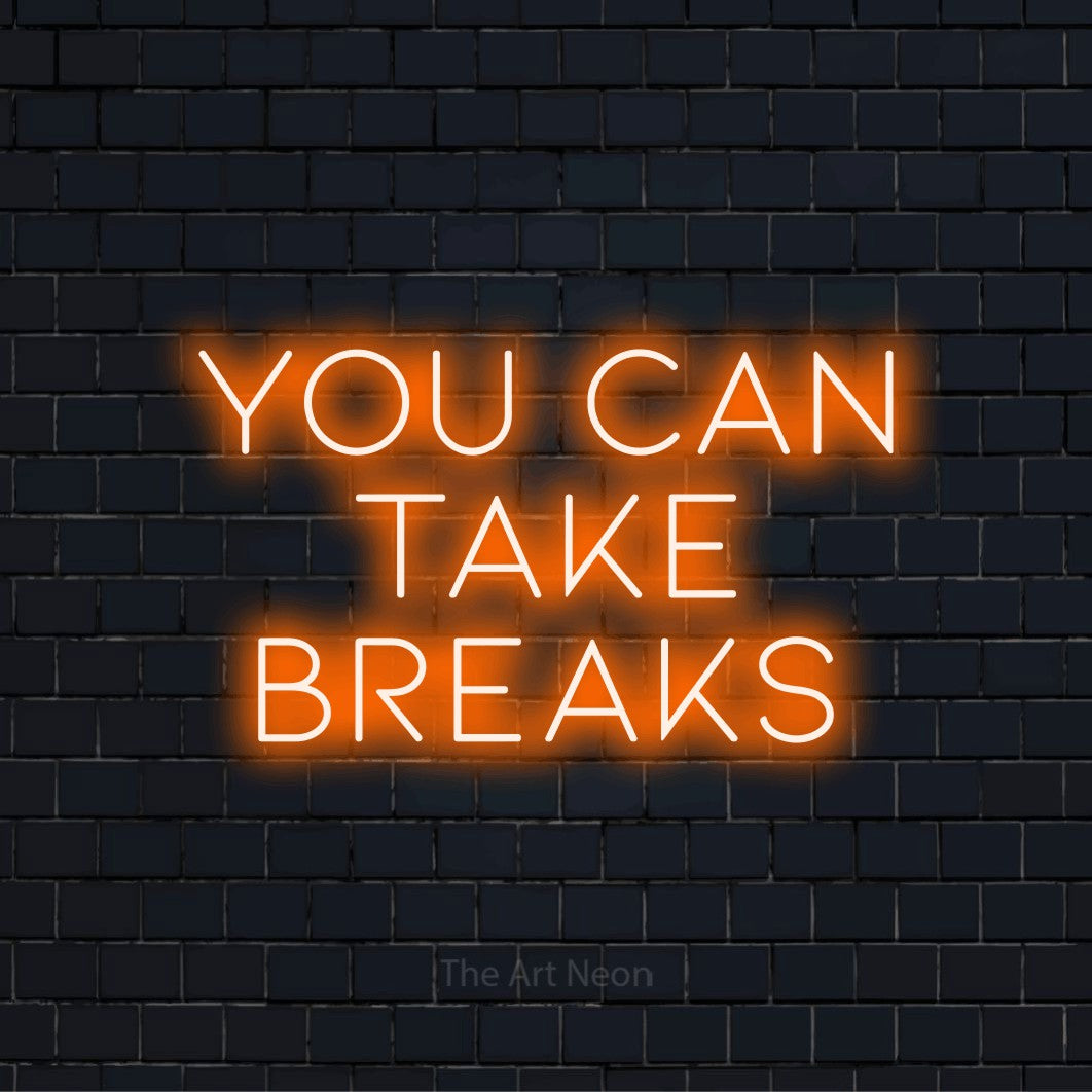 "You Can Take Breaks" script-style LED neon sign on a black brick wall
