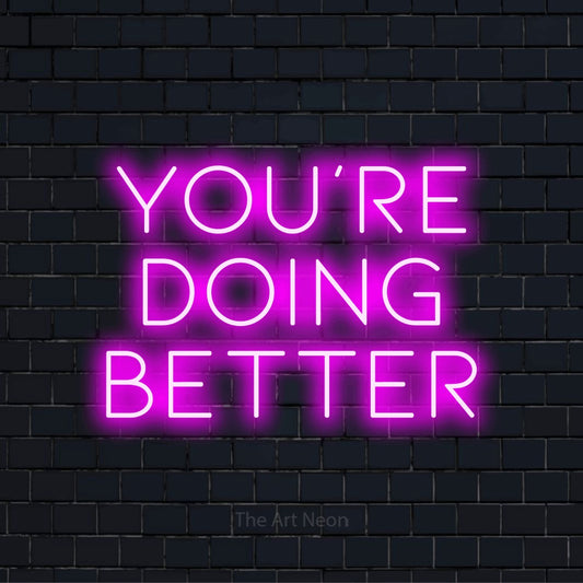 "You’re Doing Better" neon text design on a black brick wall